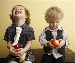 Brother and sister laughing and holding apple on table