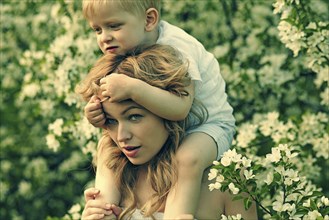 Caucasian mother holding son near flowers in tree