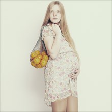 Pregnant woman carrying bag of fruit