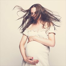 Pregnant Caucasian woman hugging her belly