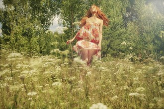 Caucasian woman twirling in field of wildflowers