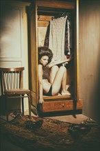 Caucasian woman sitting in wardrobe wearing underwear