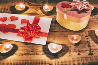 Valentine candles burning on table with gift box and card