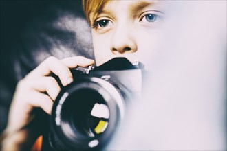 Close up of Caucasian boy holding camera