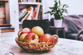 Basket of apples on wooden table in livingroom