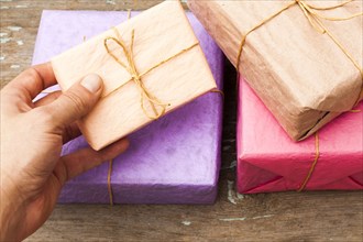 Hand holding wrapped gifts on wooden table