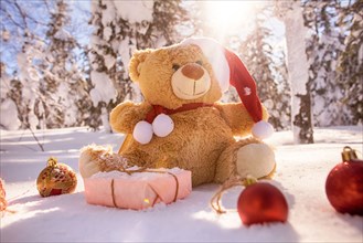 Teddy bear with Christmas gifts and ornaments in snow
