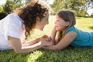 Mother and daughter laying in grass together