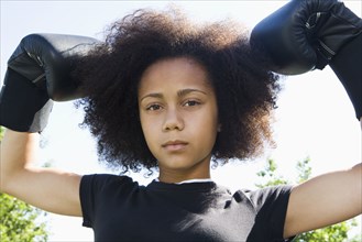 Serious teenage girl wearing boxing gloves