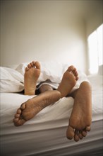 Barefeet of couple laying in bed together