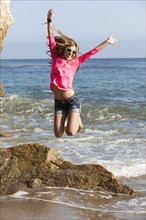 Caucasian teenager jumping on beach