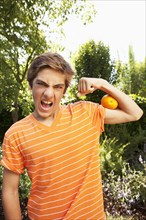 Caucasian teenager squeezing orange with arm