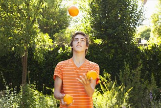 Caucasian teenager juggling oranges