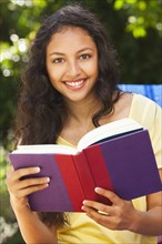 Mixed race woman reading book outdoors