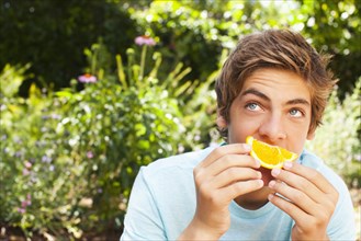 Caucasian teenager eating orange