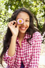 Mixed race teenager holding flower in front of her face