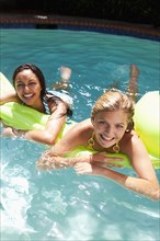 Girls laying on inflatable raft in swimming pool