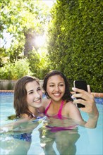 Friends in swimming pool looking at cell phone