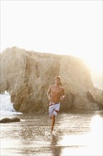 Caucasian man running on beach