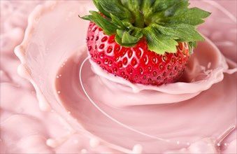 Close up of strawberry splashing in pink liquid