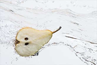 Close up of halved pear splashing in water