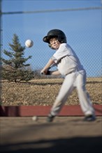 Caucasian boy hitting baseball on field