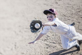 Caucasian boy catching baseball on field