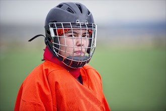 Mixed race field hockey goalie wearing helmet
