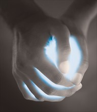 Close up of hands holding glowing blue light