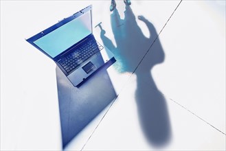 Shadow of hacker lurking over laptop computer