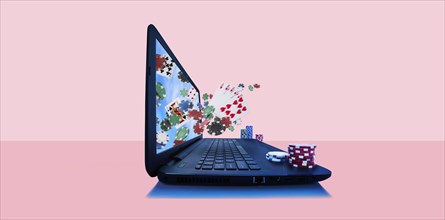 Playing cards and gambling chips emerging from laptop screen