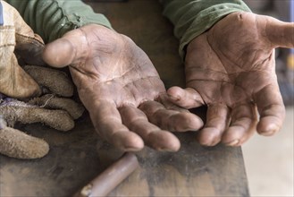 Artist leaning on table in workshop showing rugged hands