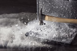 Hammer breaking ice on frozen laptop