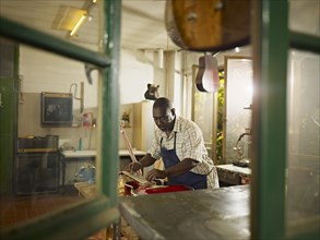 Black lute maker working in workshop