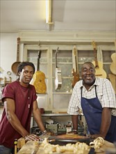 Black craftsman in guitar workshop with son