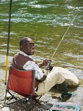 Smiling Black man fishing in stream