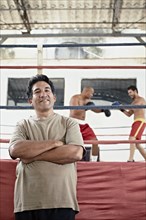 Hispanic trainer standing next to boxers fighting in ring