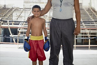 Hispanic trainer standing with boy in boxing gear