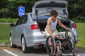 Caucasian paraplegic woman unloading wheelchair from car