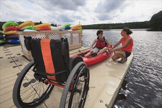 Caucasian instructor helping paraplegic woman with kayak