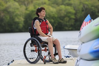 Caucasian paraplegic woman sitting on dock