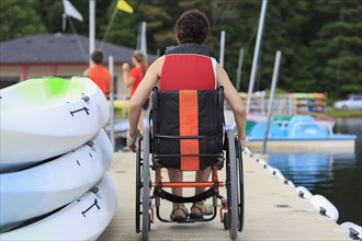 Caucasian paraplegic woman sitting on dock