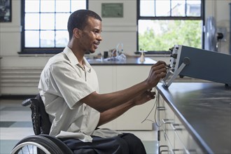 African American paraplegic student performing experiment in science classroom