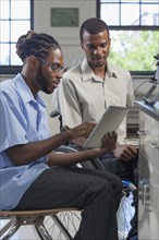 Paraplegic student and classmate using digital tablet
