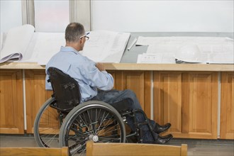 Caucasian architect in wheelchair talking in office