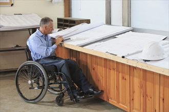 Caucasian architect in wheelchair working in office