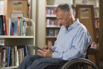 Caucasian man using digital tablet in library