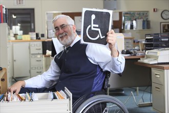 Caucasian businessman holding handicapped sign in office
