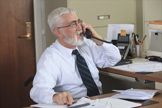 Caucasian businessman talking on phone in office