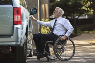 Caucasian businessman in wheelchair opening van door